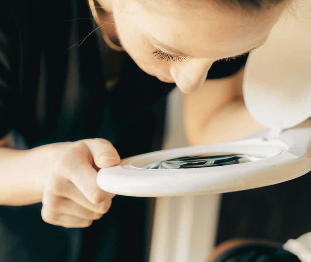 Esthetician examining client's skin with magnifying lamp during pre-microneedling skin assessment at Cumming GA med spa