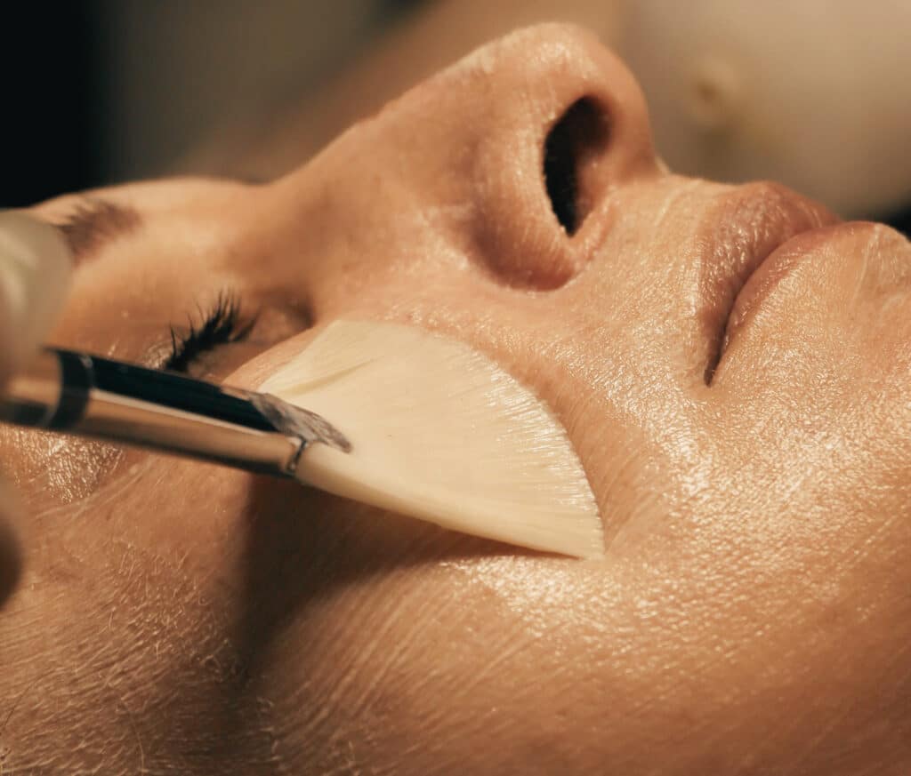 Close-up of a facial mask being applied with a brush to glowing skin during a professional facial treatment at Good Chemistry med spa in Cumming, GA