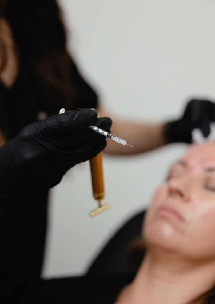 Black-gloved injector preparing a Xeomin syringe and vibration tool before treating fine lines at a Cumming, GA med spa