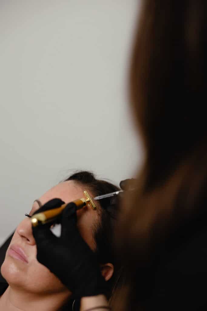 Black-gloved injector preparing a Xeomin syringe and vibration tool before treating fine lines at a Cumming, GA med spa